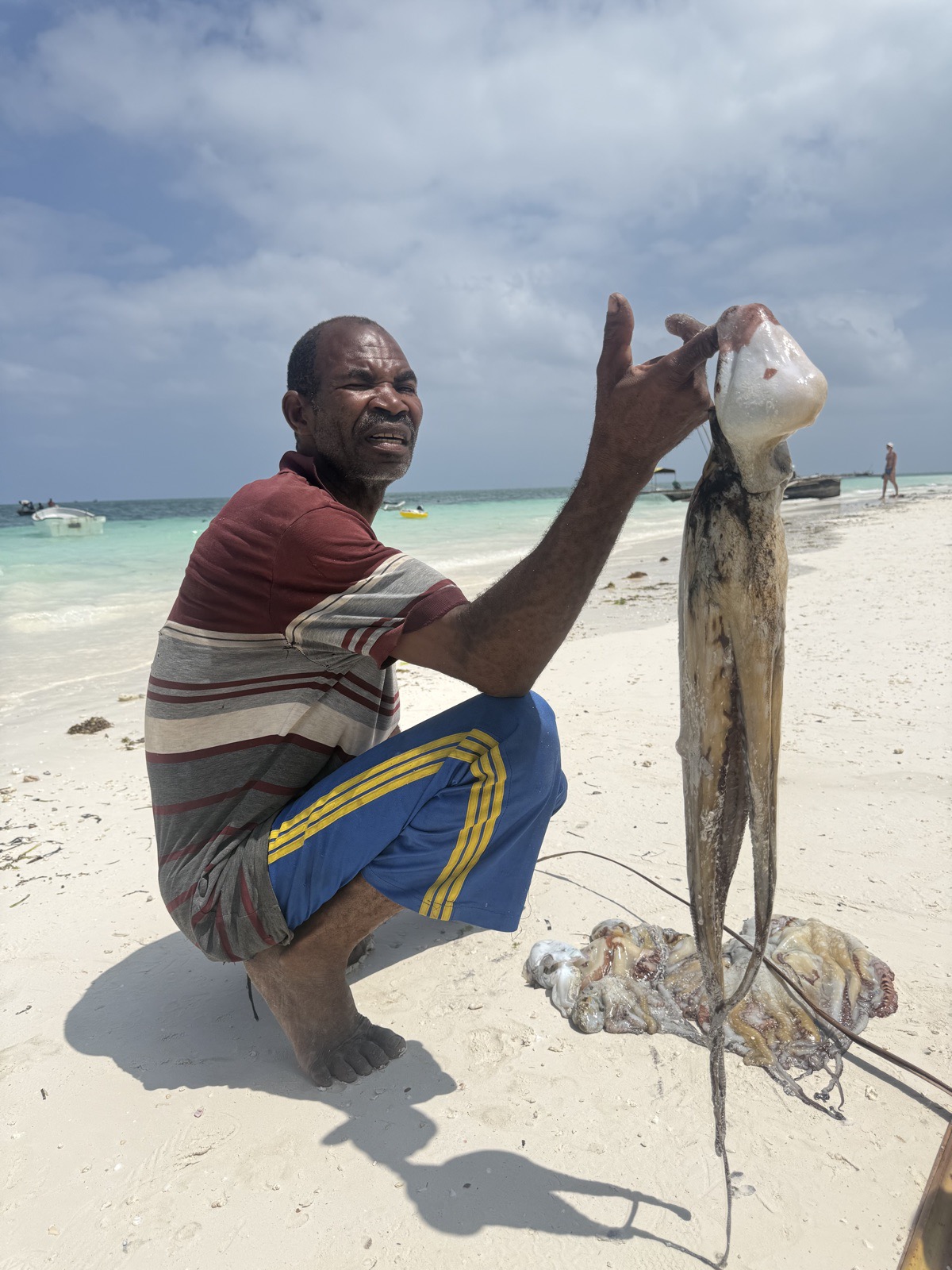 Pescatore con un polpo appena pescato sulla spiaggia